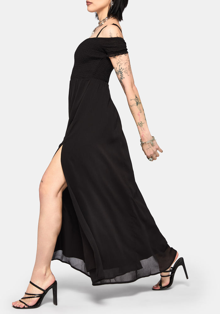 Woman wearing a black off-shoulder maxi dress with a thigh high slit on a white background