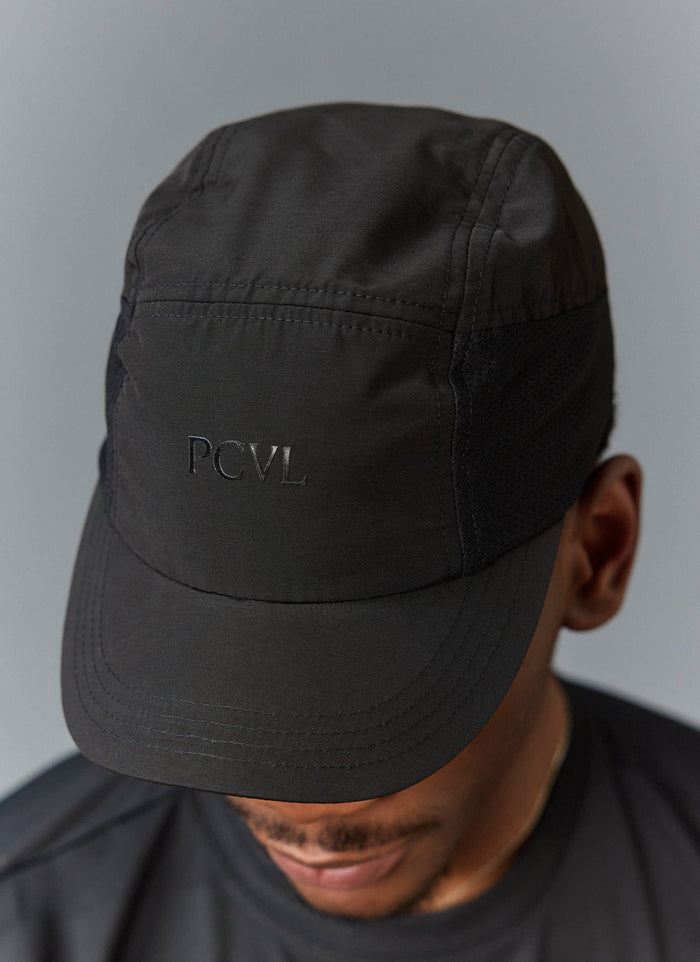 Close up of a model wearing the Percival black nylon PCVL cap, showing the tonal logo on the front.