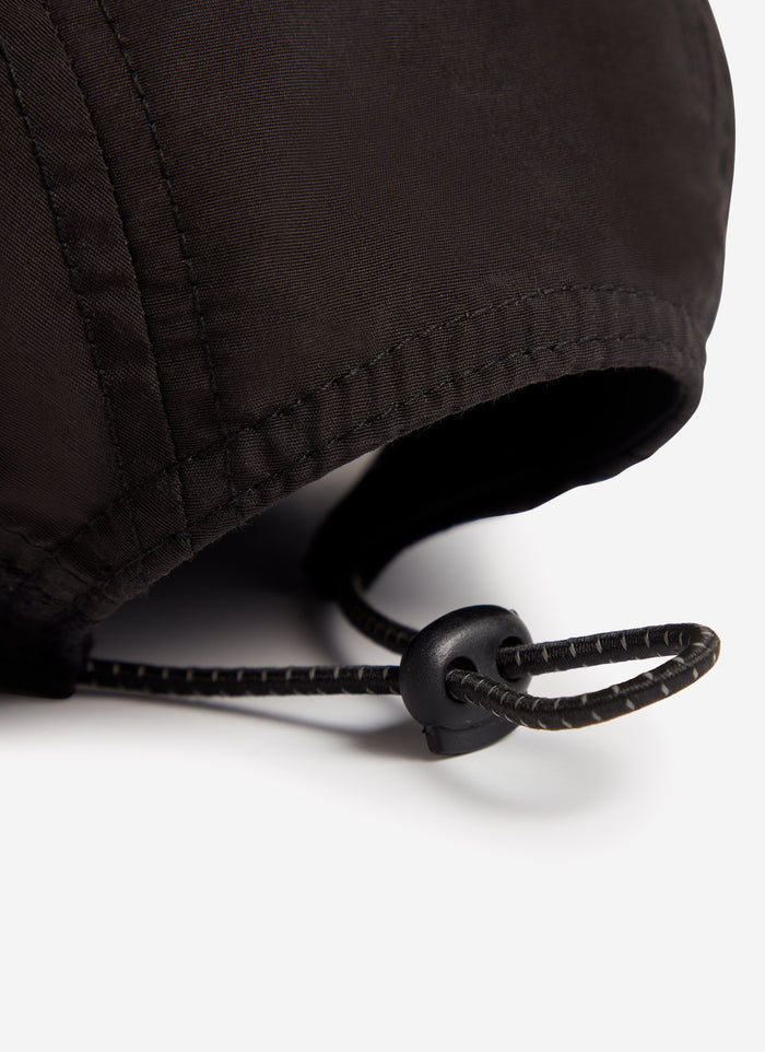 Close-up on the adjustable toggle fastening at the back of the black nylon PCVL cap from Percival.