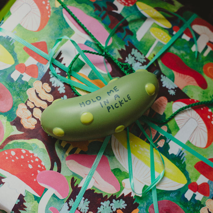 Pickle-shaped stress ball with “HOLD ME IN A PICKLE” on colorful fabric