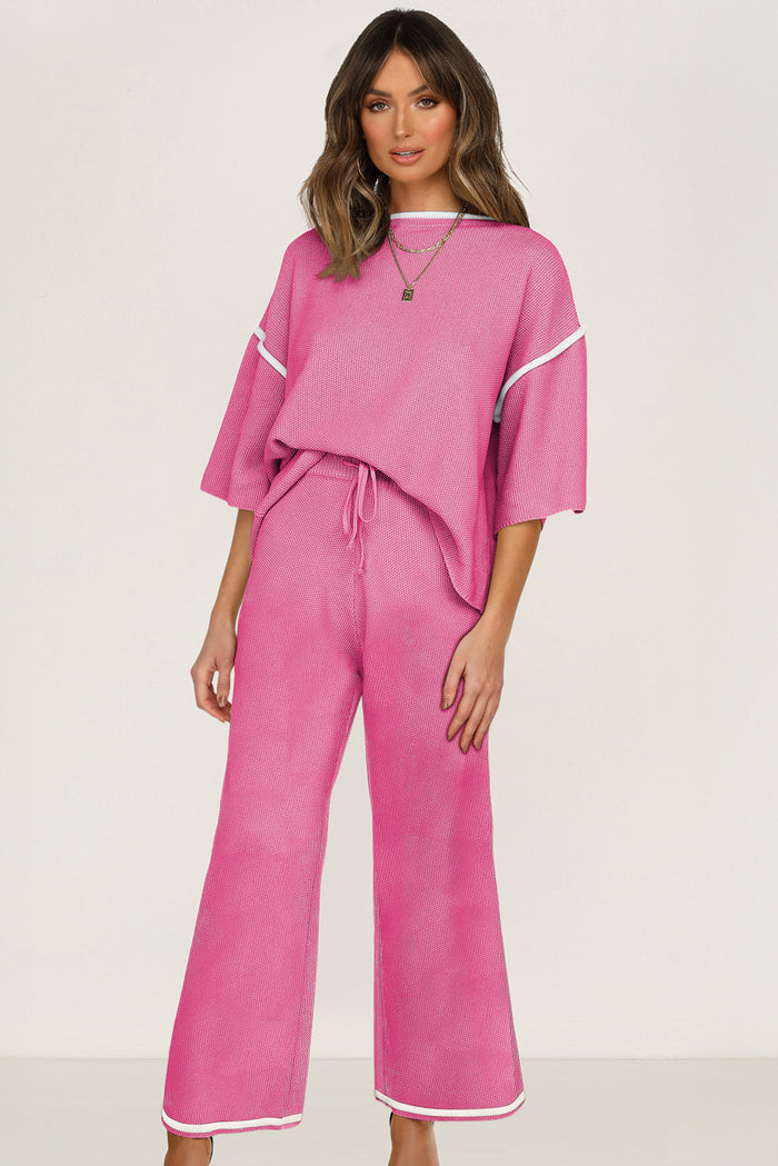 Woman wearing a pink knit sweater set with contrast trim, featuring a half sleeve top and high-waisted drawstring pants.