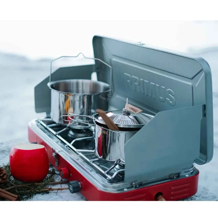 Primsu Atle gas stove being used to cook a camp meal in the snow using both burners with pans