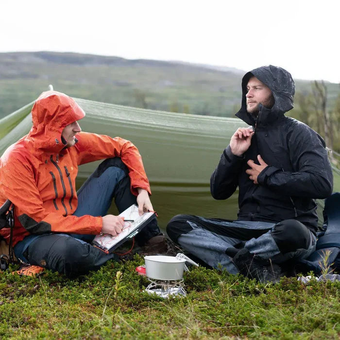 Two people in raincoats sitting outdoors  whilst camping using a Primus Gravity Camping Gas Stove to cook a meal