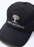 Close-up of the Percival x The Gorilla Brand Earth Day cap in black, highlighting the white embroidered tree design.