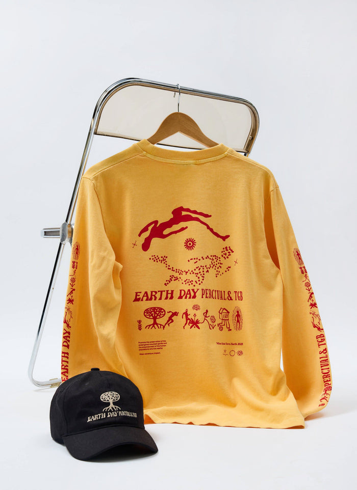 The Percival x The Gorilla Brand black cap and yellow t-shirt from the Earth Day collection, styled on a chair.