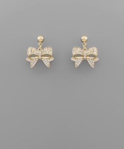 Gold-tone ribbon bow dangle earrings with cubic zirconia accents on a gray background from The Pink Doxie Boutique.