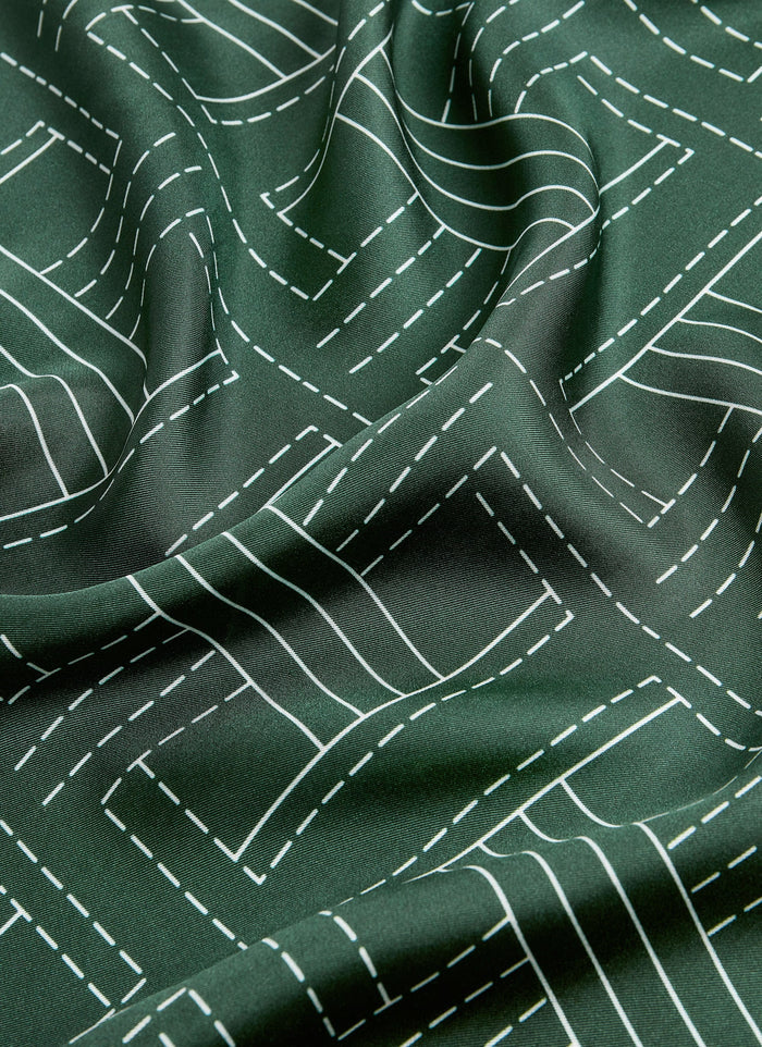 A close-up shot of the forest green silk fabric of the Sashiko Neckerchief by Percival, showing the white stitch pattern.