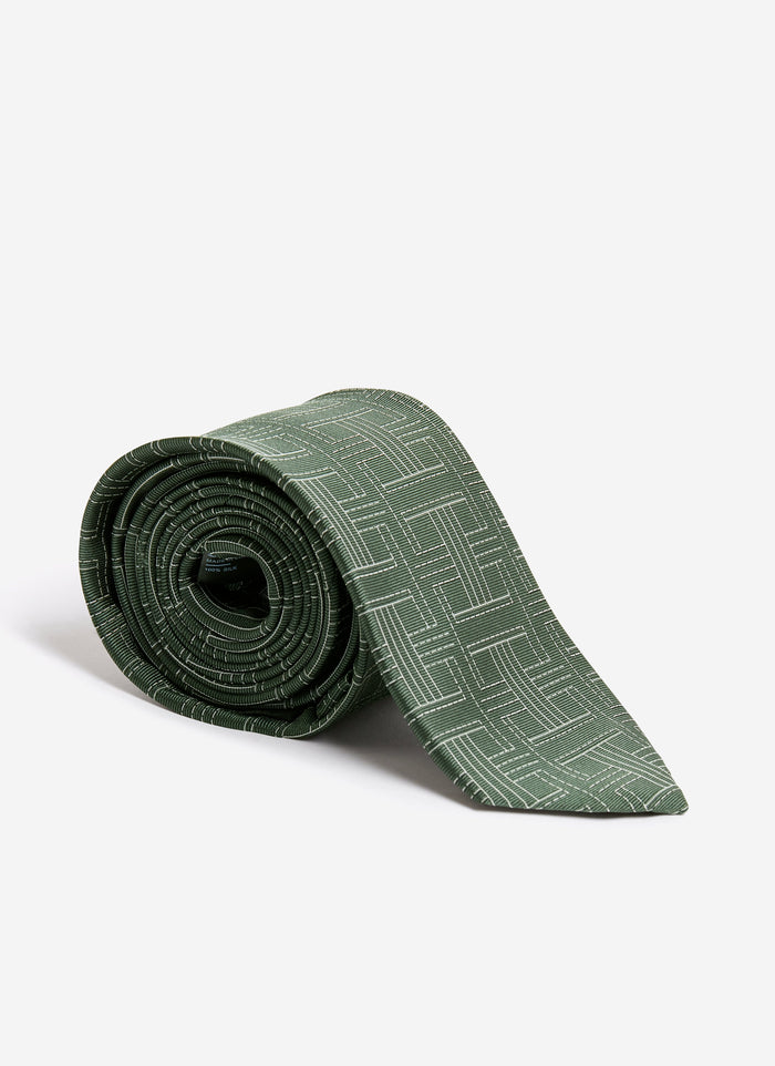 The Percival Sashiko Tie in forest green silk, rolled up to show its textured sashiko-inspired weave.