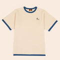 The Sassy Woof x Sunbean Human Tee by Sunbean is a beige short-sleeve t-shirt with blue collar and sleeve cuffs, featuring a small embroidered dog on the left chest.