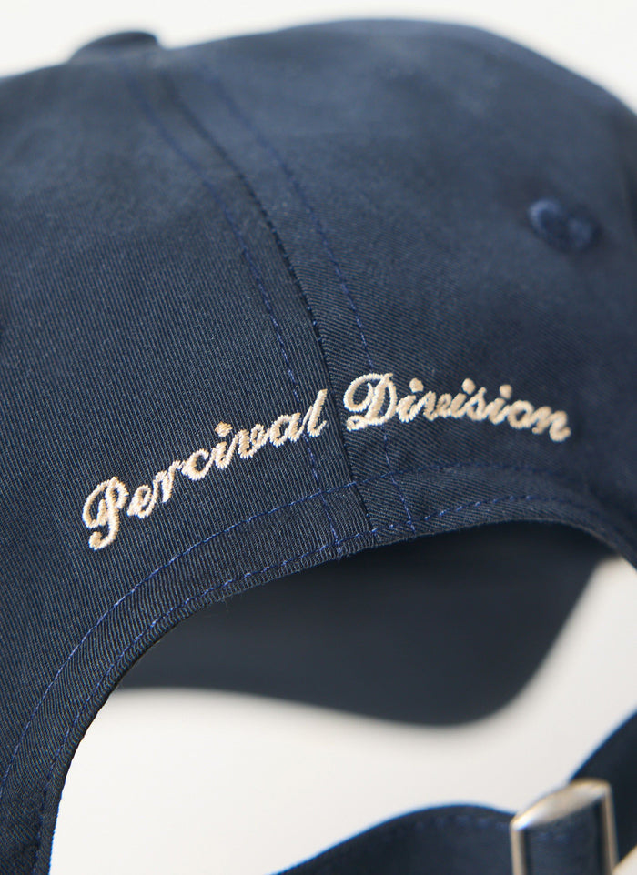 Close up of the navy Percival trucker cap showing the 'Percival Division' ecru embroidery on the back.