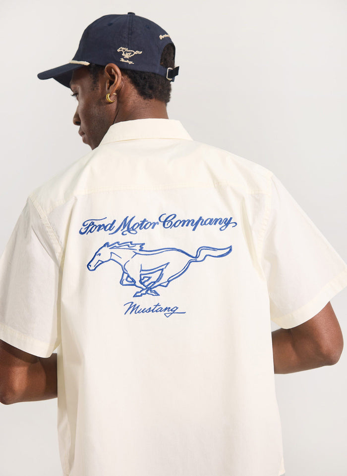 Model from behind in the ecru Percival x Ford Pit Crew shirt and navy Soft Trucker Cap, showing the back embroidery.