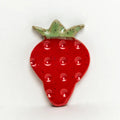 Strawberry-shaped red ceramic refrigerator magnet with green leafy top and speckled glaze