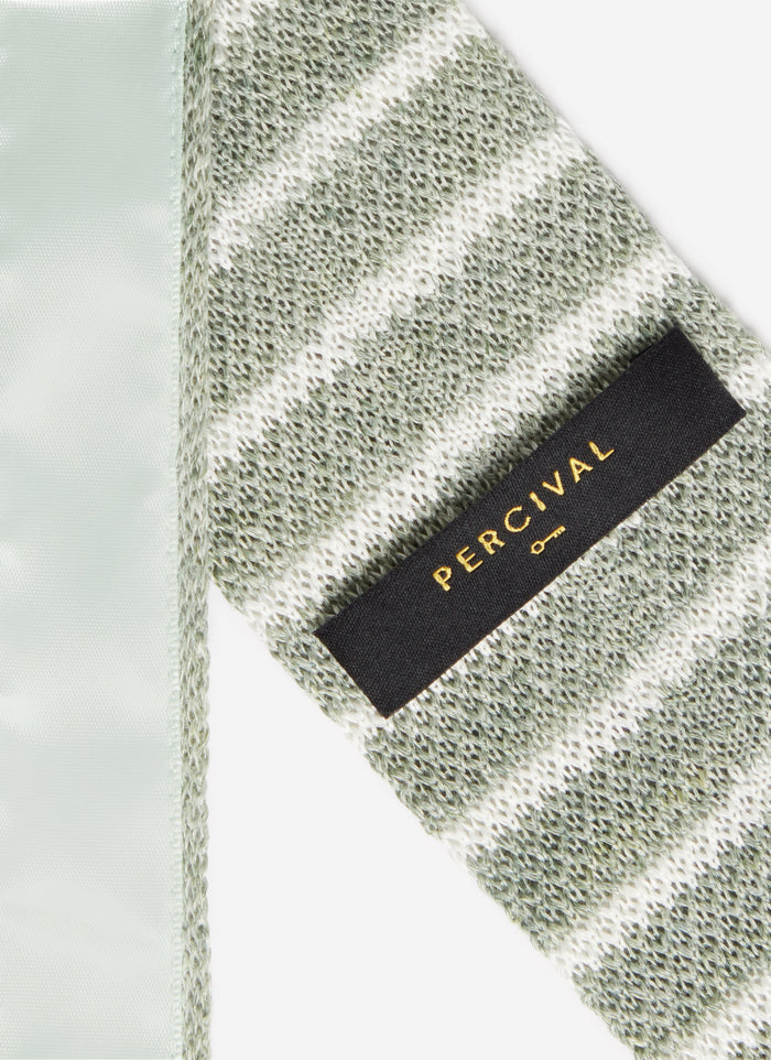 A close-up of the back of the Percival Stripe Linen Tie in Forest Marl, showing the black and gold logo and knitted texture.