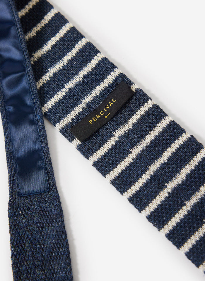 Close up of the Percival navy marl and white striped linen tie showing the brand label and knitted texture.