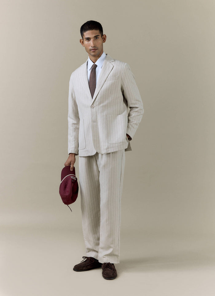 A model wears the Percival cream striped tailored linen-blend blazer and matching trousers in a studio setting.