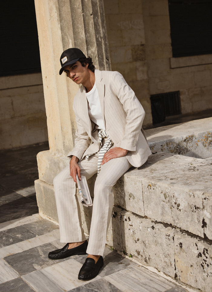 A model wears the cream Percival striped tailored blazer and trousers, styled with a white t-shirt and black loafers.