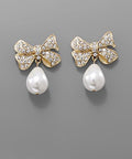 Teardrop pearl bow earrings with crystal accents in gold and silver tones displayed on a neutral background from The Pink Doxie Boutique.