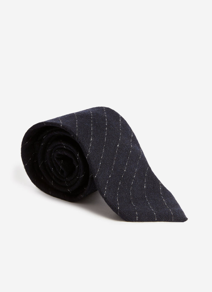 The Percival Textured Stripe Tie in navy, neatly rolled to showcase its subtle pinstripe detail on a white background.