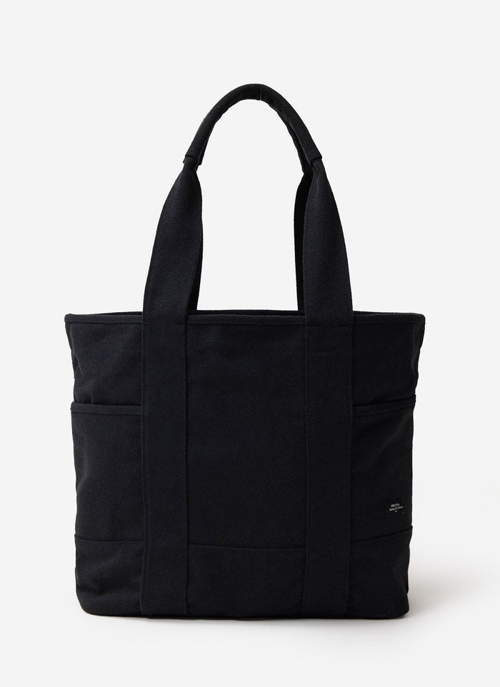 The Percival Tote Bag in black heavy-weight canvas, featuring sturdy handles and external pockets, shot in a studio.