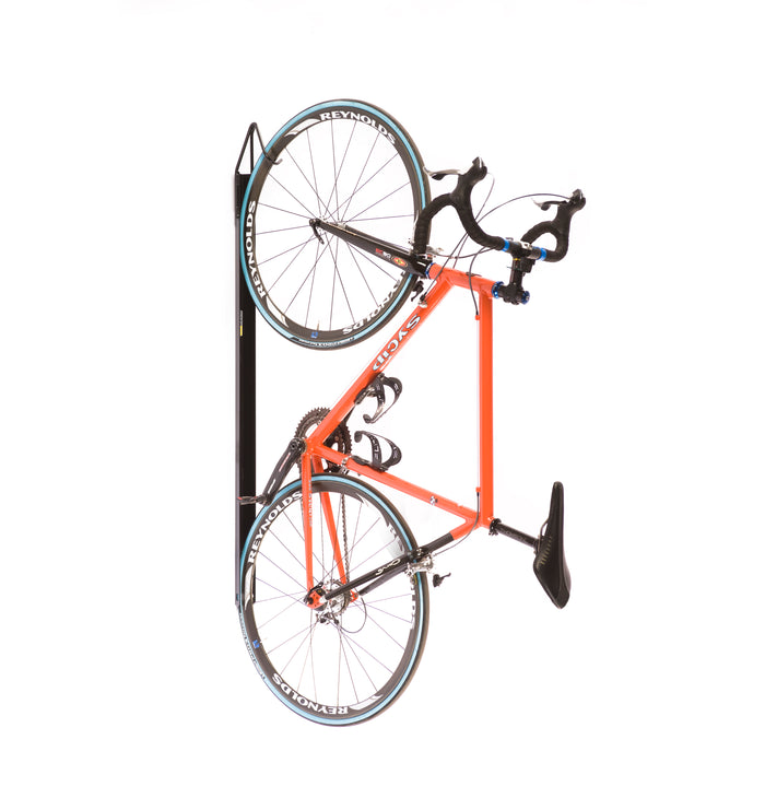 Saris Universal Bike Trac holding orange road bike vertically against wall in garage