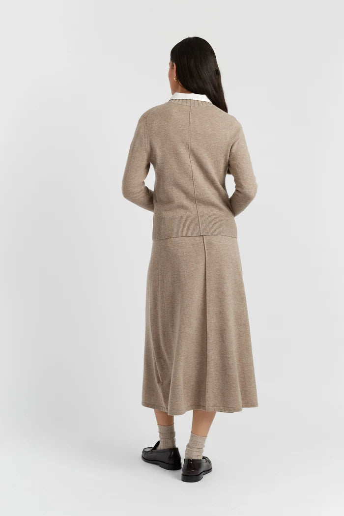 Woman wearing a beige cardigan and skirt set on a white background