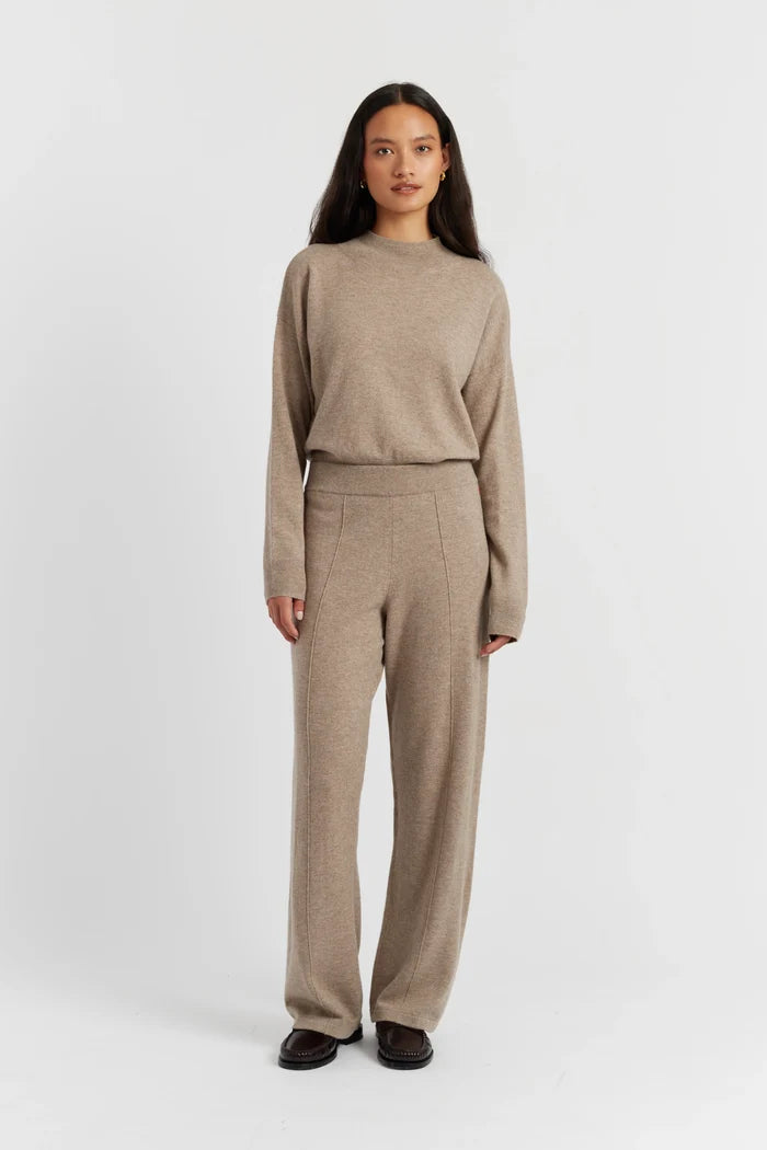 Woman wearing a beige sweater and pants set on a white background