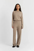 Woman wearing a beige sweater and pants set on a white background