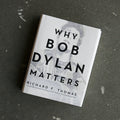 Book titled "Why Bob Dylan Matters" by Richard F. Thomas, white cover with bold black type