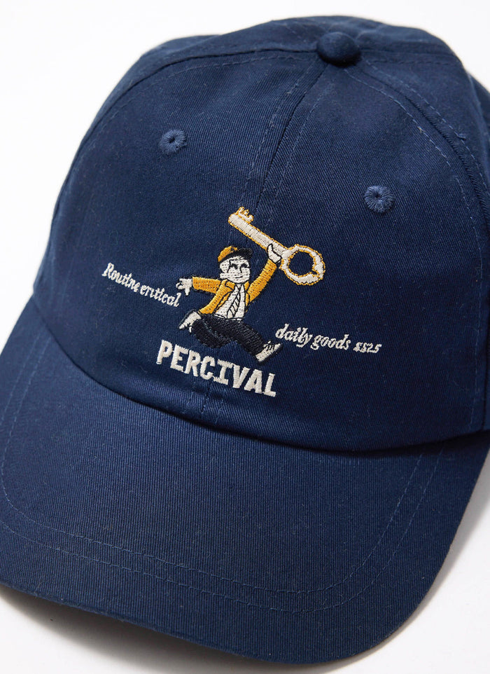 A close-up of the navy cotton World Key Cap by Percival, detailing the 'man with a key' embroidery on the front.